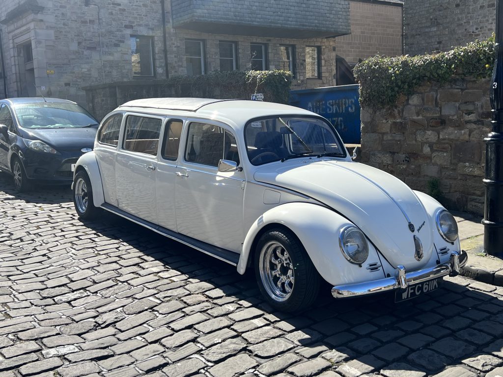 Daisy, a white 1972 stretched VW Beetle limousine, parked on a cobbled street