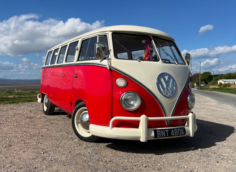 Bobrico, a red and cream 1972 15-window splitscreen VW bus, parked by the coast