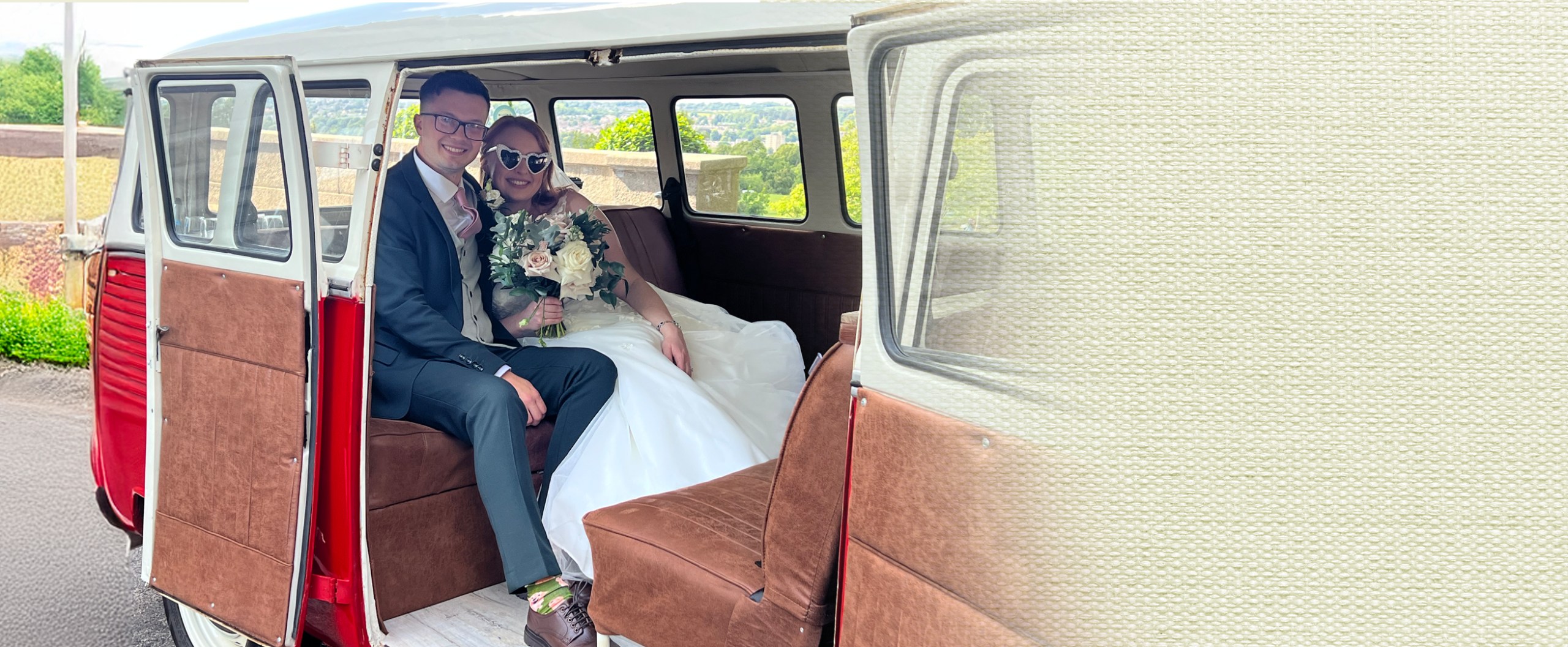 Bride and groom sitting together in the open side door of the vintage VW campervan wedding car