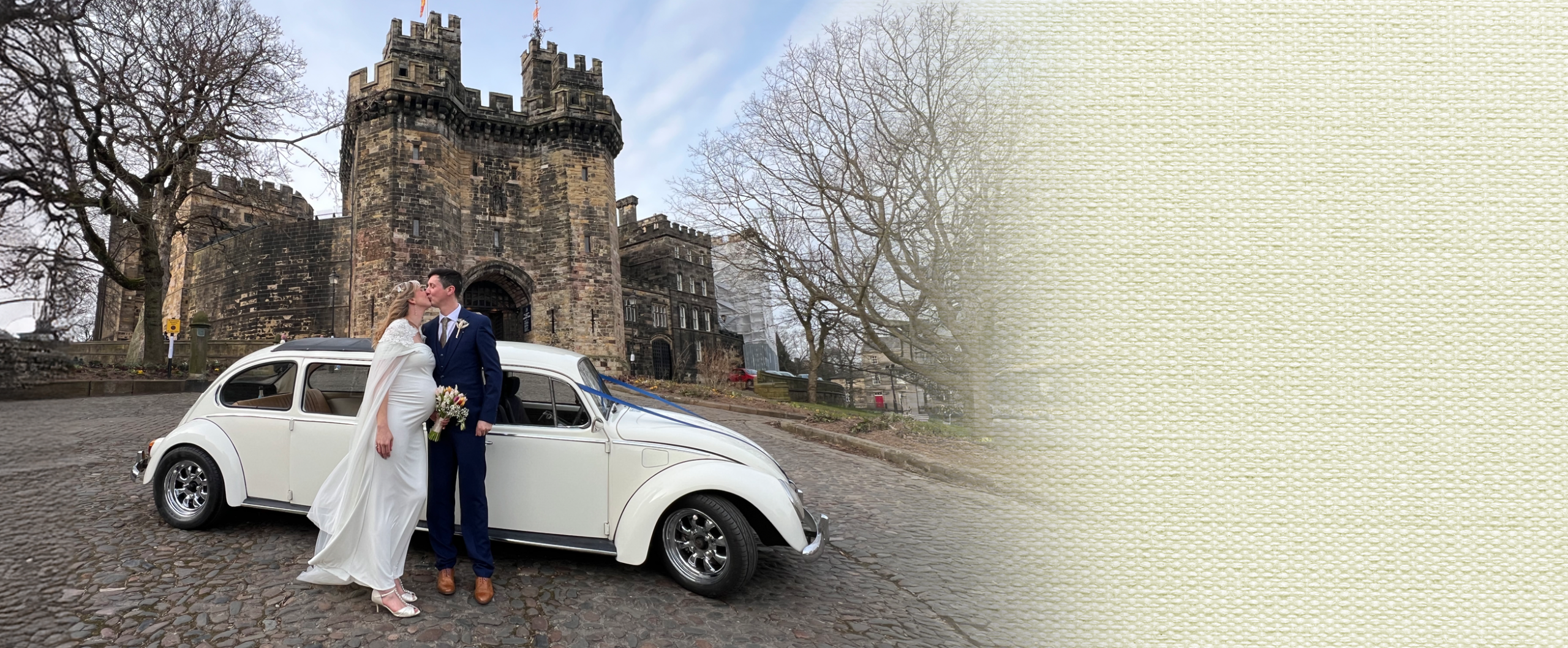 Bride and groom beside a cream vintage VW Beetle wedding car on a cobbled street